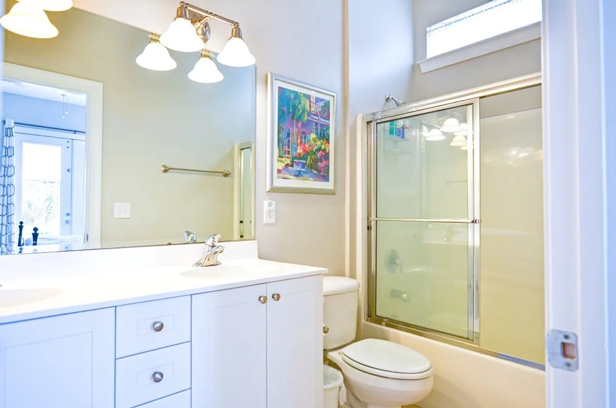 A fresh, modern bathroom with a sleek vanity, glass shower enclosure, and framed artwork. Morning light filters in, creating an inviting space for self-care and convenience.