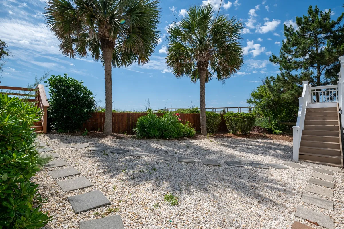 A tranquil outdoor area with palm trees, a stone pathway, gravel sections, and verdant landscaping. The space radiates a serene, natural vibe—ideal for unwinding after a day of adventure or as a launching point for exploring nearby parks and the beach.