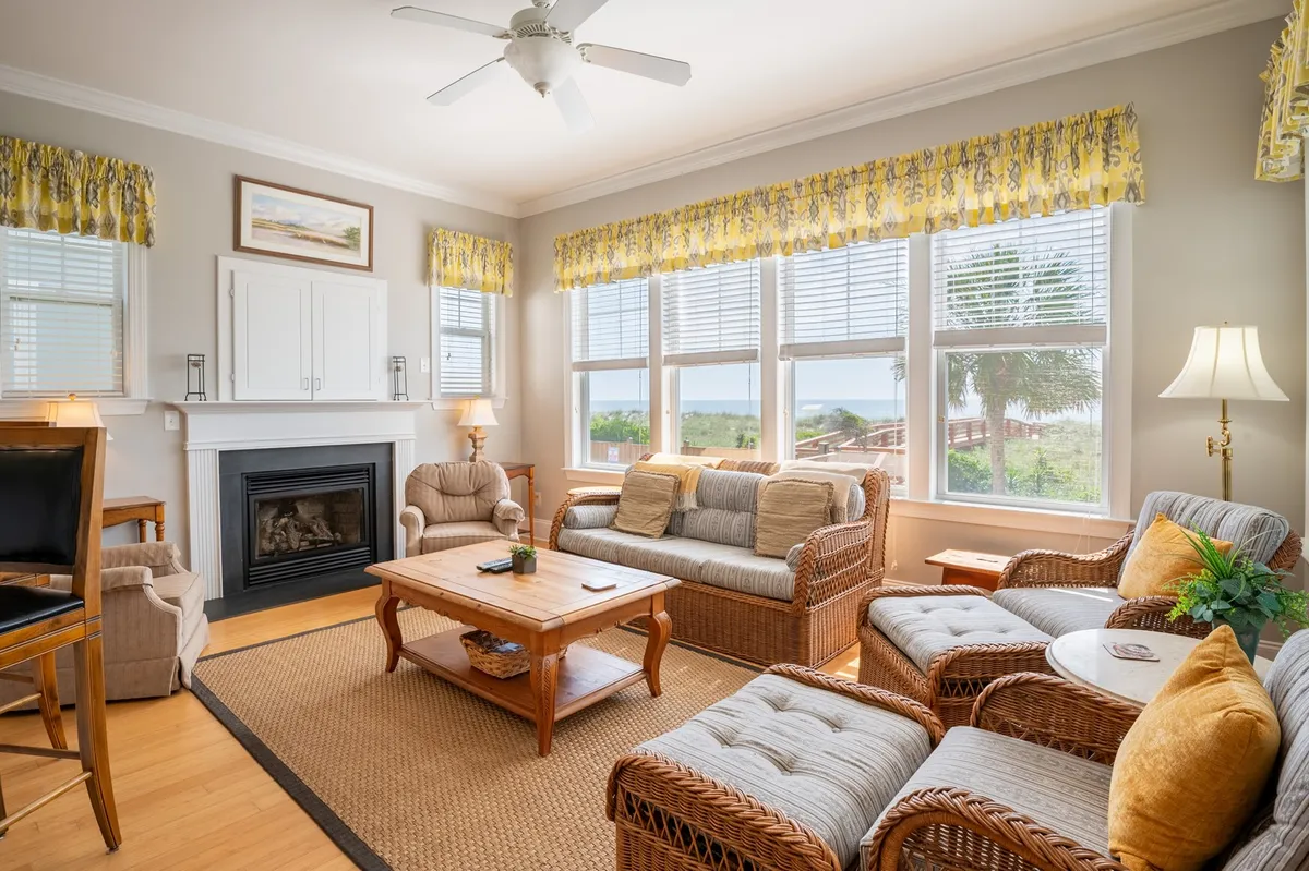 A living area featuring comfortable seating, a fireplace, a coffee table, and large windows letting in natural light. The space conveys warmth, perfect for relaxing, playing games, or enjoying quiet moments with a scenic backdrop.