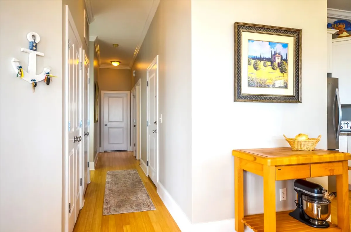 A warm, decorated hallway with wall art, a wooden table, and nautical decor sets a welcoming tone. The space feels inviting and personal, suggesting shared areas that foster connection while leading to individually secured homes.