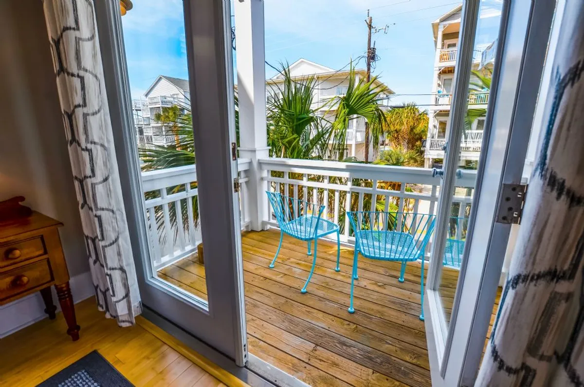 A wooden deck with blue chairs and palm trees, offering a peaceful spot to relax with an ocean view. The setting is ideal for family meals, game nights, or simply enjoying the ocean breeze after a day of adventure.